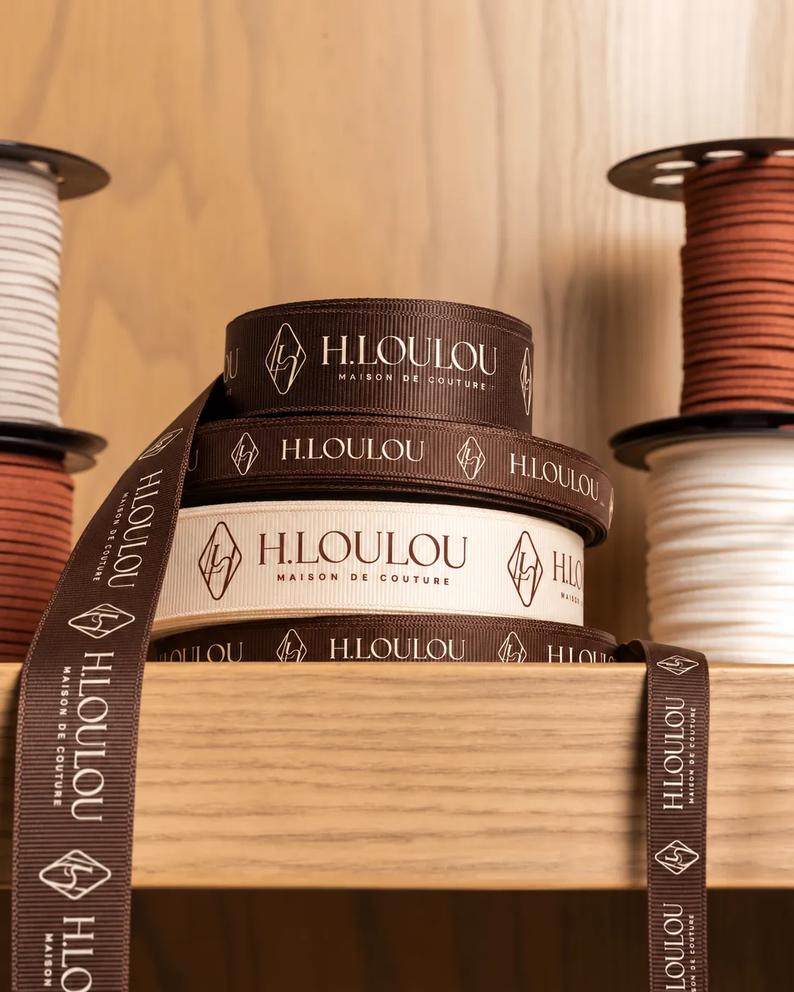 Illustrative grosgrain ribbons carrying the H·LOULOU mark